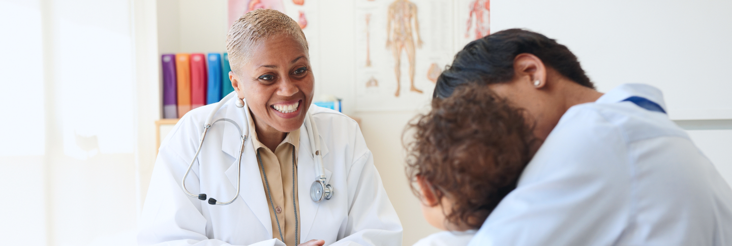Médecin qui sourit à une fillette et son parent