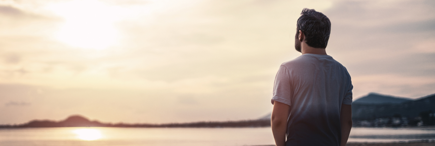 Homme au bord de l’eau fixant l’horizon